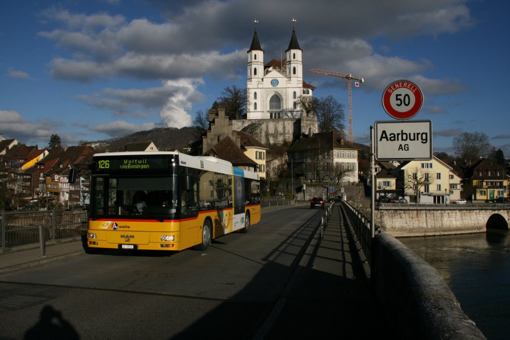 Vor der Kulisse der Kirche und der Festung Aarberg ist am 18.1.2010 der MAN SO 59'314 von PU Wyss unterwegs in Richtung Boningen. Er berquert mit dieser Brcke gleichzeitig auch die Aargauisch-Solothurnische Kantonsgrenze. 