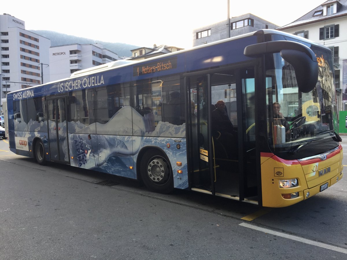 Das Ortsbus Brig - Glis Ersatzfahrzeug im PostAuto Design trägt jetzt auch auf der anderen Seite eine Werbung, nämlich für Mineralwasset Swiss Alpina von Coop, am 3.12.16 auf dem Bahnhof Brig.