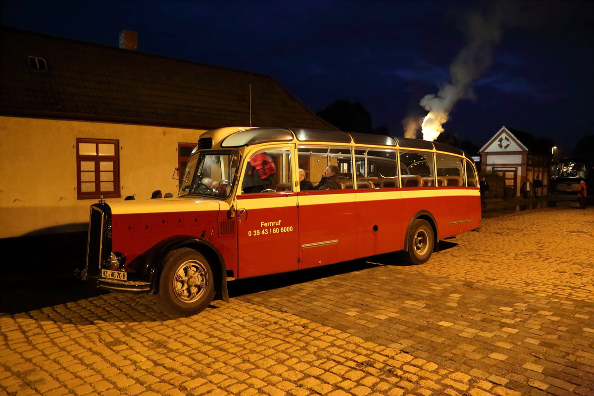 Ein Saurer Postauto (Alpenwagen) L4C Typ IIIa am Abend des 23.10.2016 auf dem Bahnhofsvorplatz in Gernrode. Das Fahrzeug wurde 1959 in der Schweiz gebaut und verkehrte dort als Postbus. Angetrieben wird es von einem 6-Zylinder-Dieselmotor mit 125 PS, welcher dem Fahrzeug eine Maximalgeschwindigkeit von ca. 74 km/h verleiht. Der heutige Eigentümer ist die Schlossbahn Wernigerode, welche mit diesem Fahrzeug regelmäßig Harzrundfahrten durchführt. An genanntem Datum war der Bus für die Interessengemeinschaft Harzer Schmalspurbahnen angemietet, um die Fahrgäste eines Sonderzuges von Gernrode zurück nach Wernigerode zu bringen.