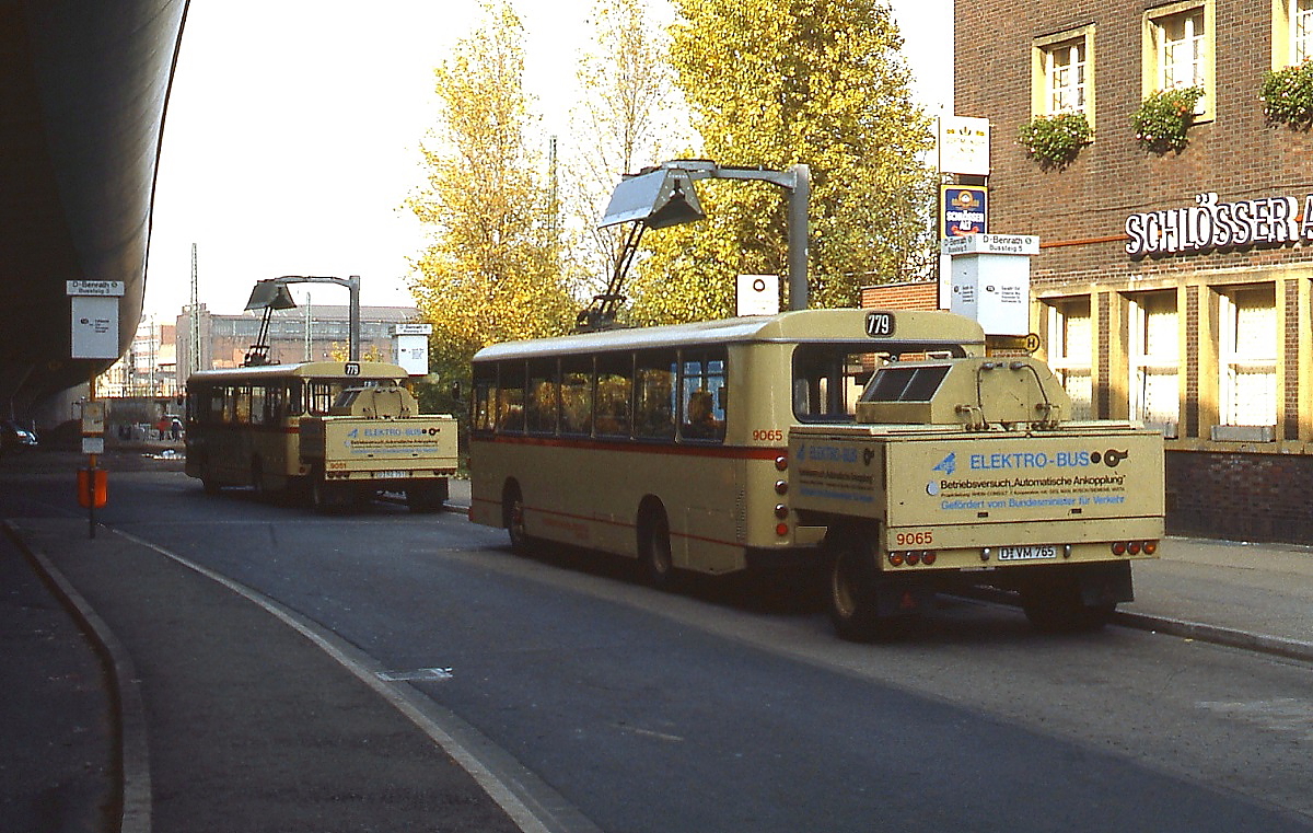 Zwischen 1975 und 1988 setzte die Rheinbahn Düsseldorf auf der Linie 39 (ab 1980 779) versuchsweise zunächst 14, später 21 Elektrobusse des Typs SL-E (Hersteller MAN/Bosch) ein, die ihre Energie aus einem mitgeführten einachsigen Anhänger bezogen. Hier stehen die Busse 9061 (vorne) und 9065 um 1980 an der Ladestation am Benrather Bahnhof. Bus 9063 ist als Museumsfahrzeug erhalten geblieben.