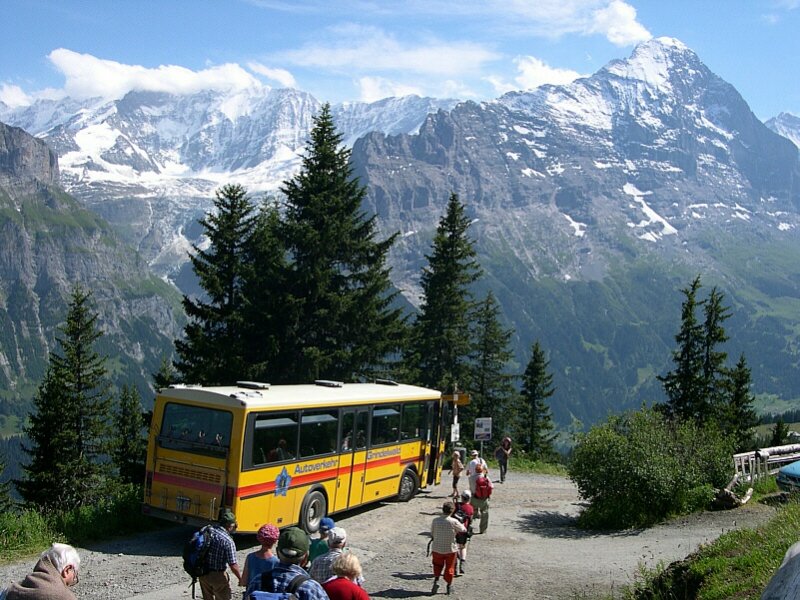 Berner Oberland 2007 - Nach einem Wendemanver auf engstem Raum, steht Grindelwald-Bus am 16.07.2007 am Waldspitz zur Fahrt nach Grindelwald bereit. Und die Fahrgste strmen ... Im Hintergrund grt der Eiger.