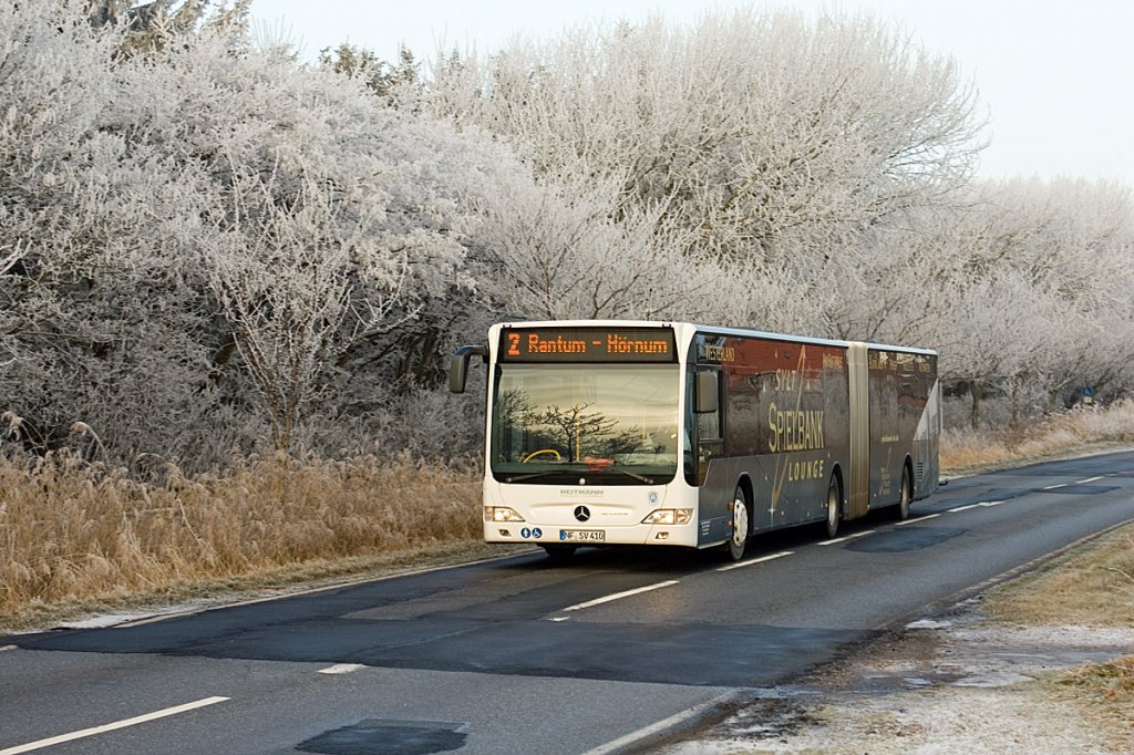 Der NF-SV 410 war am 18. Dezember 2010 von Westerland in der Mitte der Insel Sylt unterwegs auf der Linie 2 nach Hrnum im Sden der Insel Sylt. Der Bus ist kurz vor der Haltestelle Campingplatz Westerland und kommt mit Raureif berzogen Sdwldschen vorbei.
