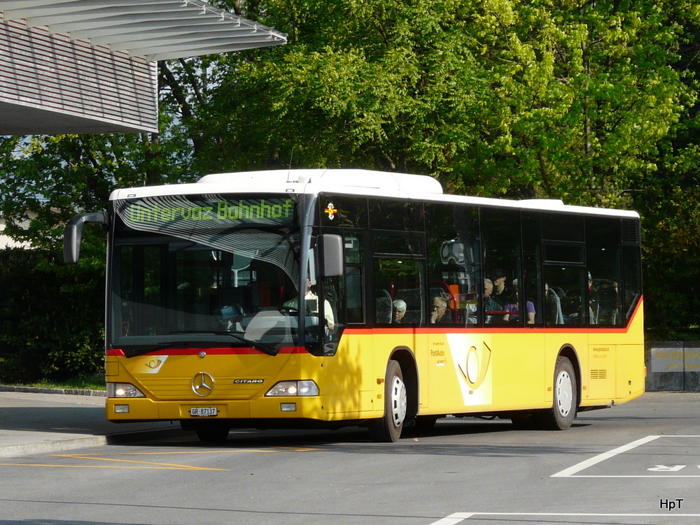 Postauto - Mercedes Citaro  GR 87137  bei den Bushaltestellen vor dem Bahnhof in Landquart am 22.04.2011