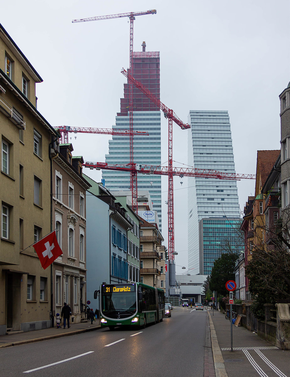 In Basel befindet sich aktuell der zweite Roche-Tower im Bau, die Planungen für einen dritten noch höheren Turm sind bereits in Gange. Vor der eindrucksvollen Kulisse der beiden Bauwerke zeigt sich Wagen 7014 der Basler Verkehrsbetriebe auf der Linie 31 kurz nach Verlassen der Haltestelle Rosengartenweg.