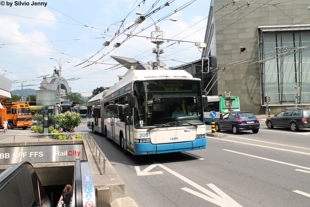 vbl Nr. 209 (Hess Swisstrolley 3 BGT-N2C) am 11.7.2013 beim Bhf. Luzern, unterwegs mit der Notfahrt infolge einer Fahrleitungsstrung, die im Hintergrund durch den vbl-eigenen Turmwagen repariert wird.