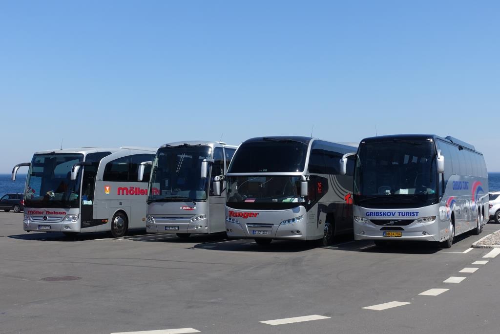 Vier silberne Reisebusse - Volvo, Neoplan, Berkhof, Mercedes, Busparkplatz an der Ostsee in Gudhjem auf der dänischen Insel Bornholm, Juni 2019