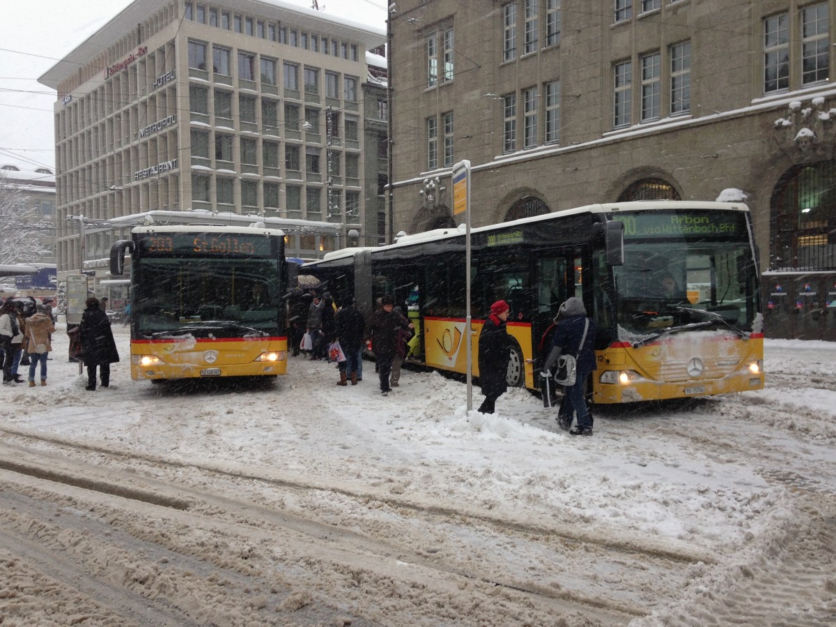 Wintereinbruch in St. Gallen: Postauto Citaro II G und Citaro I G auf dem Bahnhofplatz, 30.12.2014.
