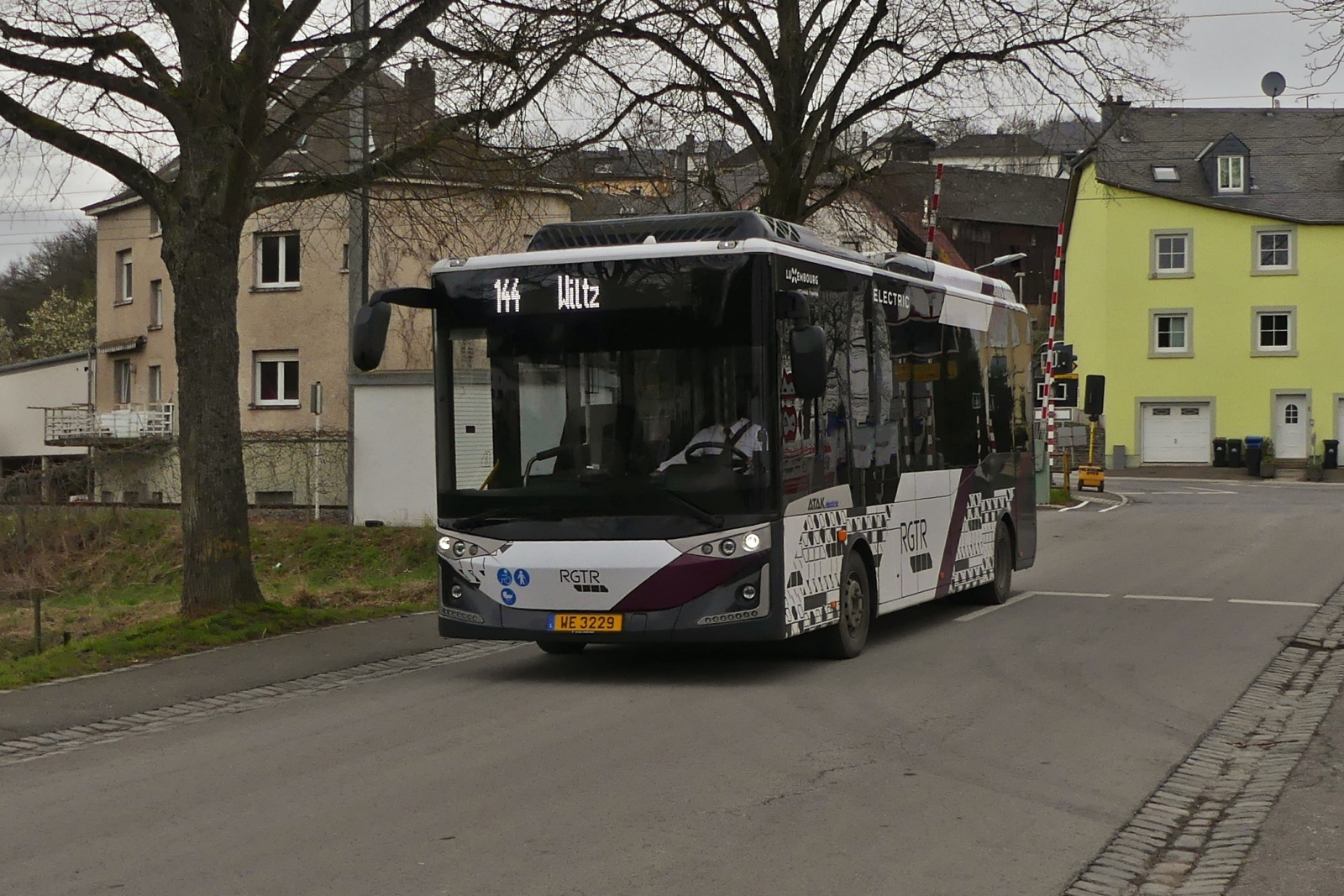 WE 3229 Karsan Atak, von WEmobility, auf der Linie 144, Park Hosingen – Licee Wiltz unterwegs, hat soeben die Bahnlinie in Wilwerwiltz berquert. 03.2024