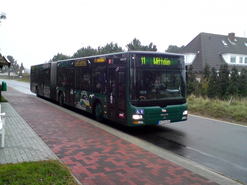 MAN Gelenkbus der Wyker Dampfschiff Reederei (W.D.R.) auf Amrum. Der Bus verlässt gerade die Haltestelle Süddorf in Richtung Wittdün. Der Bus trägt innen und außen Werbung für das Hotel und Café Hüttman in Norddorf. Aufgenommen am 23.10.2009